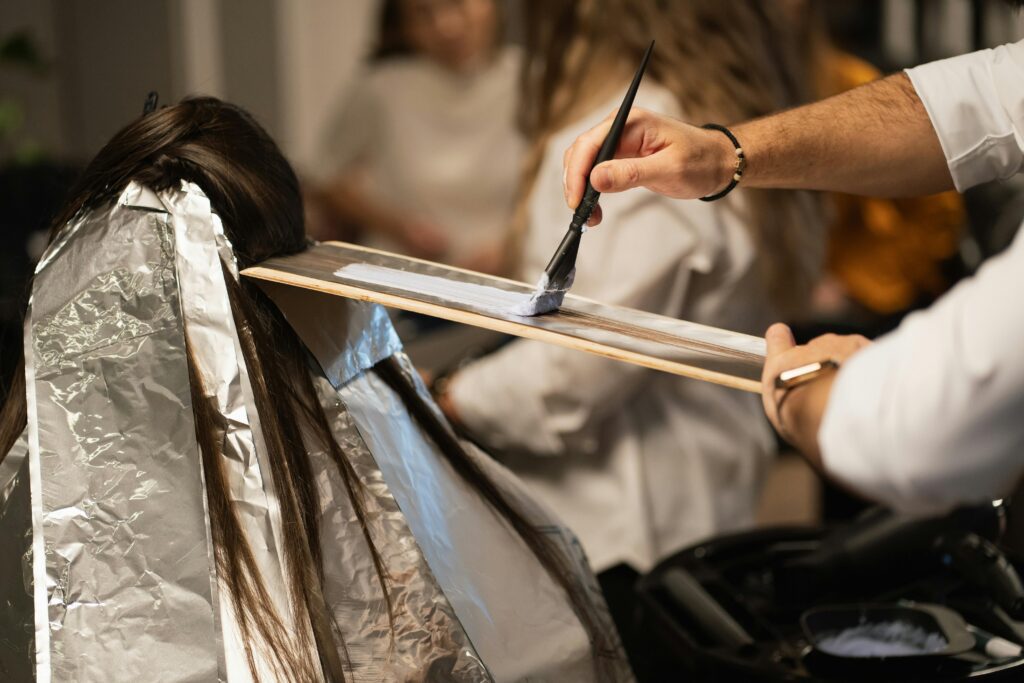 pexels-photo-20894394-20894394 Hairdresser applying dye to client's hair with precision, showcasing modern salon hair coloring techniques.