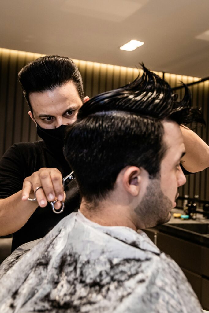 pexels-photo-5568411-5568411 Barber styling a client's hair with precision in a modern barbershop.