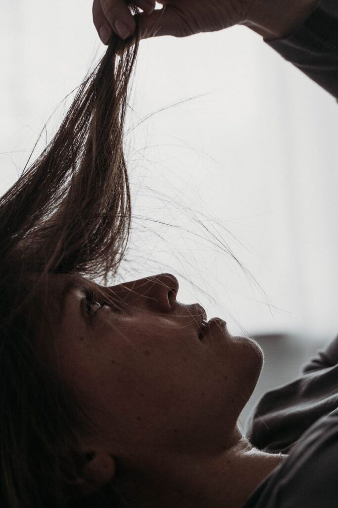 Side view of a woman lying in bed holding her hair thoughtfully indoors.