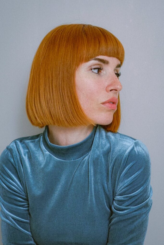 Modern portrait of a woman with copper bob haircut and velvet blue top.