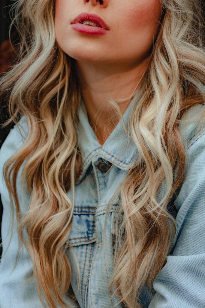 pexels-photo-14153837-14153837 Stylish close-up shot of a blonde woman wearing a denim jacket with wavy hair.