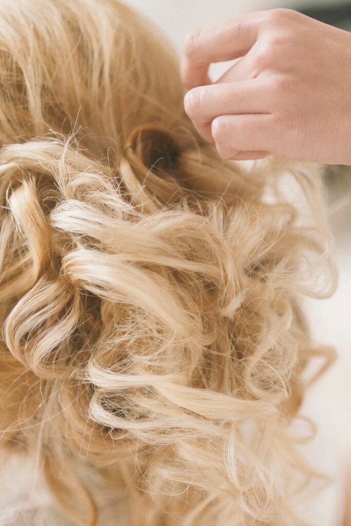 A professional hairstylist creates a blonde bridal updo for a wedding.