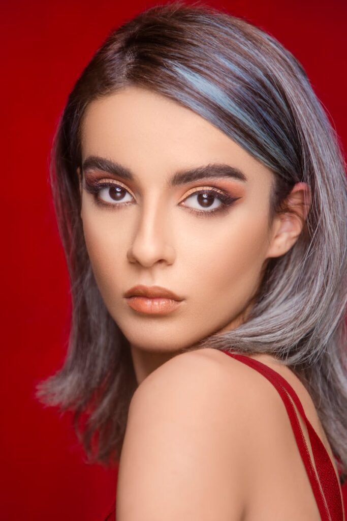 pexels-photo-17697574-17697574 Portrait of a stylish woman with dyed hair against a vivid red background.