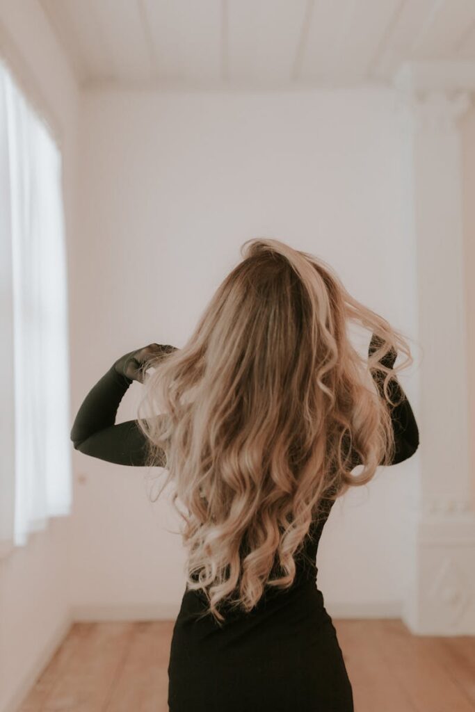 pexels-photo-31052908-31052908 Elegant long blonde hair styled in waves captured from behind in a minimalist indoor space.