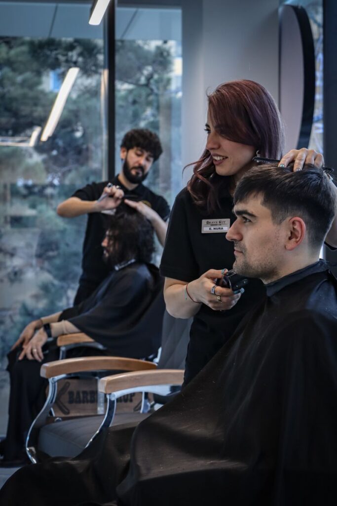 pexels-photo-33448213-33448213 Barber and stylist working on clients in a contemporary salon environment, capturing the art of hairstyling.