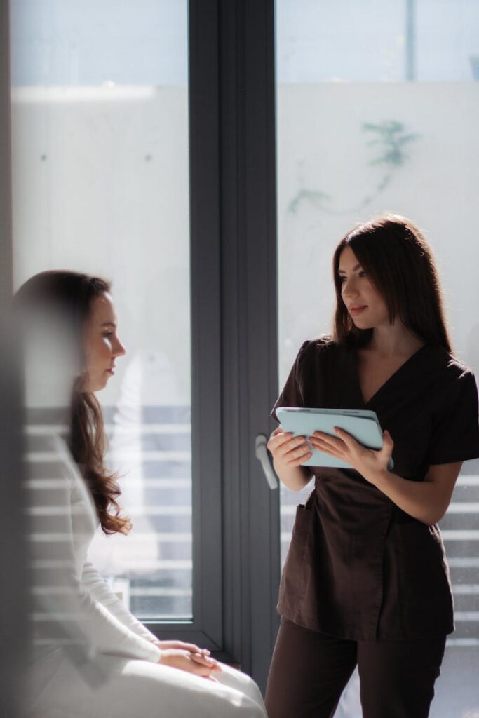 Two women in a modern office setting engaged in a consultation, using a tablet.
