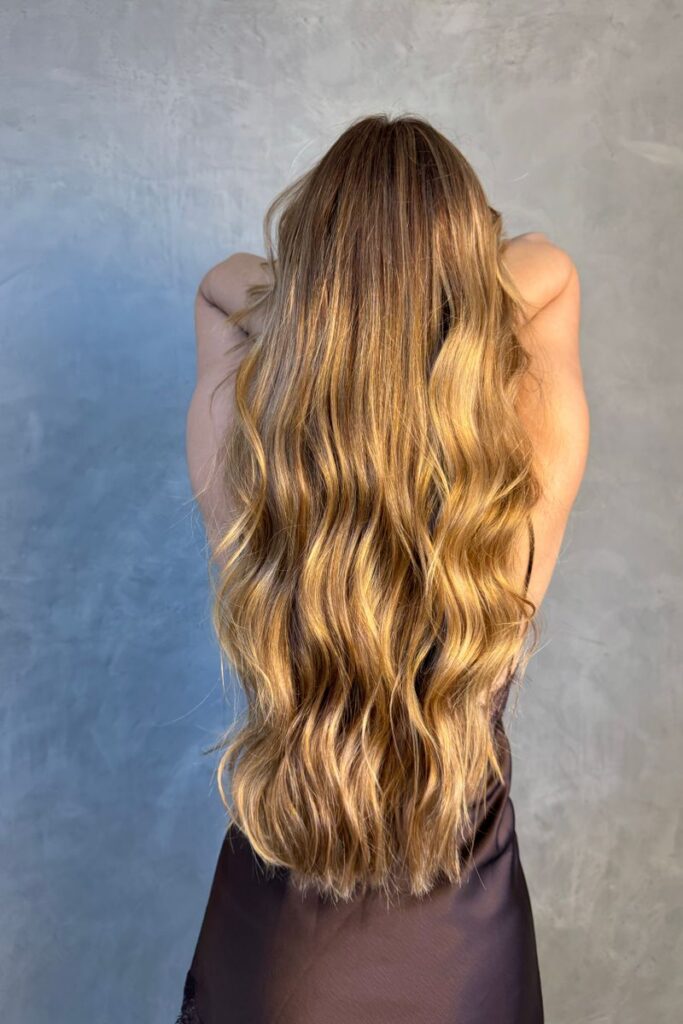 Model with flowing wavy blonde hair showcasing hairstyle in studio setting.
