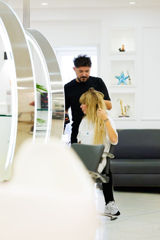pexels-photo-35225397-35225397 Hairdresser styling client's hair in a sleek, modern salon with contemporary decor.