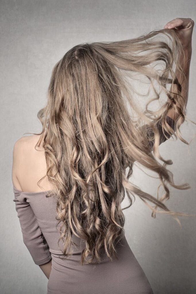 pexels-photo-3782002-3782002 A stylish woman in an off-shoulder outfit, posing with wavy hair indoors.