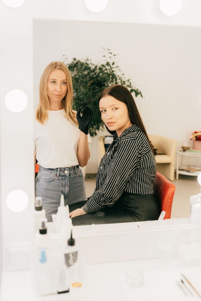 pexels-photo-5178007-5178007 Makeup artist applying cosmetics to client in a modern salon with vanity mirror.