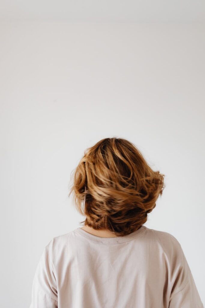 pexels-photo-7273415-7273415 A back view of a woman with short blonde hair against a plain white backdrop, offering ample copy space.
