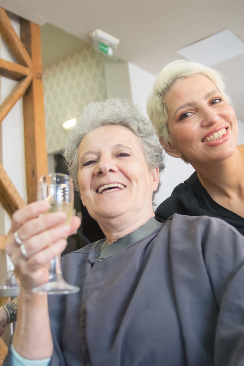 Happy senior woman and hairstylist smiling in a hair salon in Portugal.